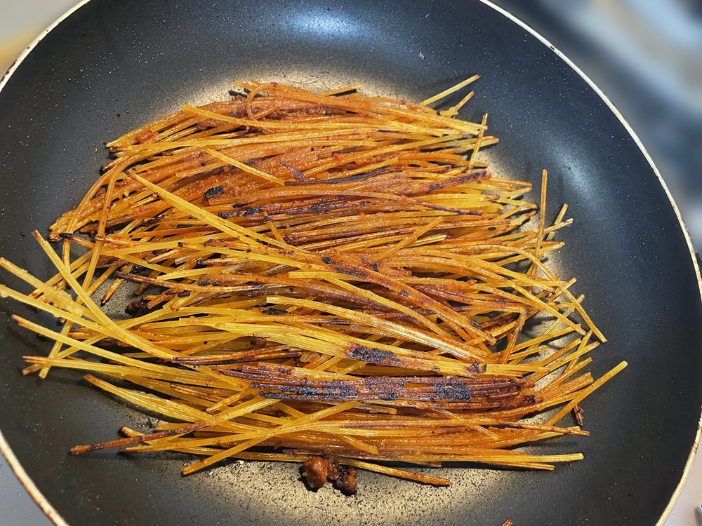 フライパンに投入したパスタが、ボロネーゼと絡み合って美味しそうなお焦げが出来てきた
