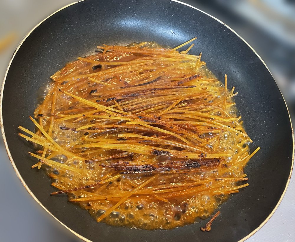 フライパンの中のパスタとボロネーゼがぐつぐつと煮立っている様子