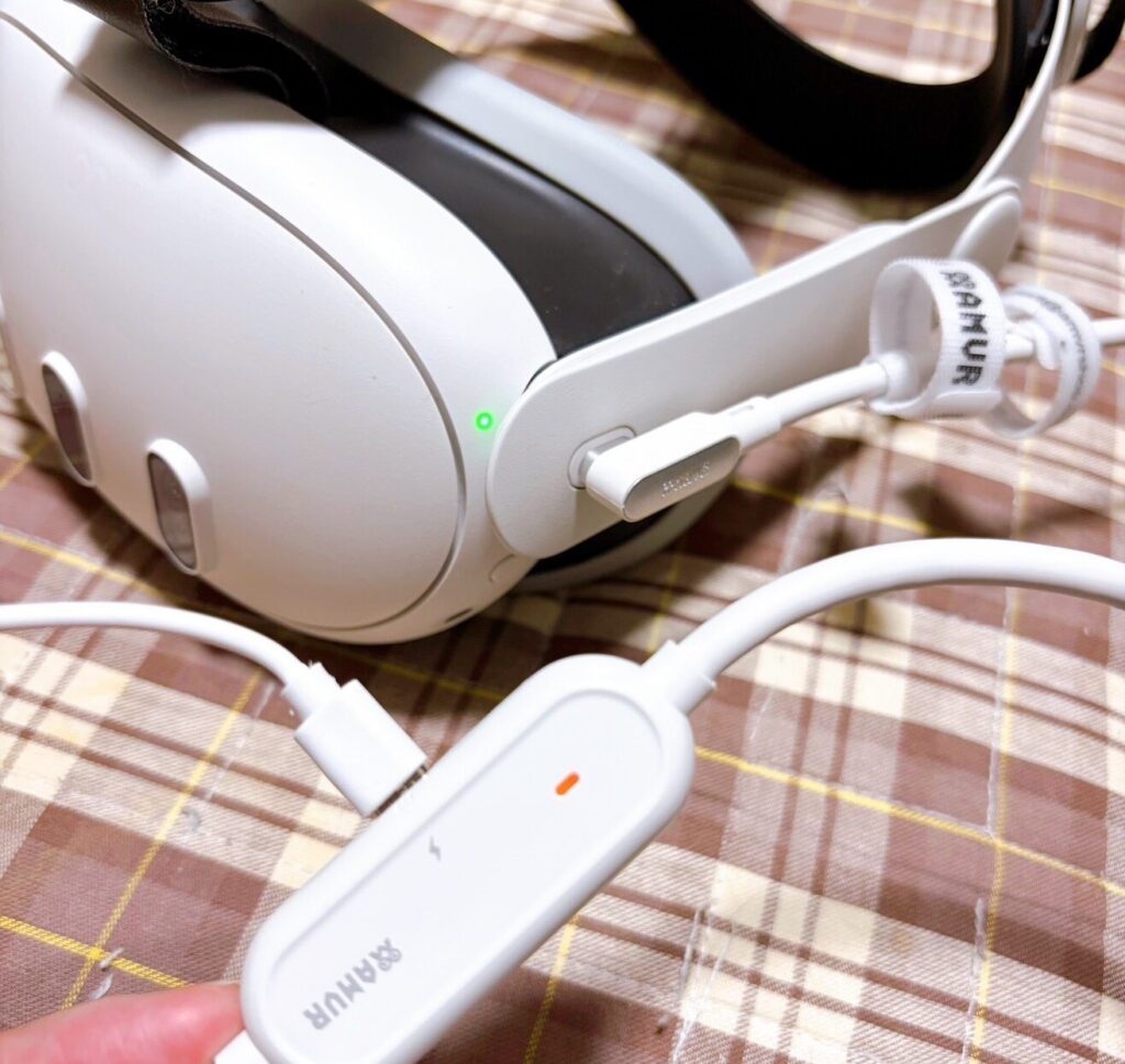 MetaQuest3にAMVR製の充電ケーブルを挿した様子。手前には給電用のパーツが見えている。