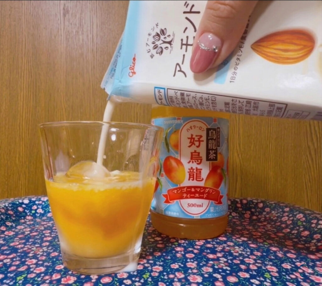 好烏龍(ハオウーロン)が入ったグラスに、グリコのアーモンド効果を注いでいる様子。見た目は良いが味は「全然美味しくない」アレンジ。