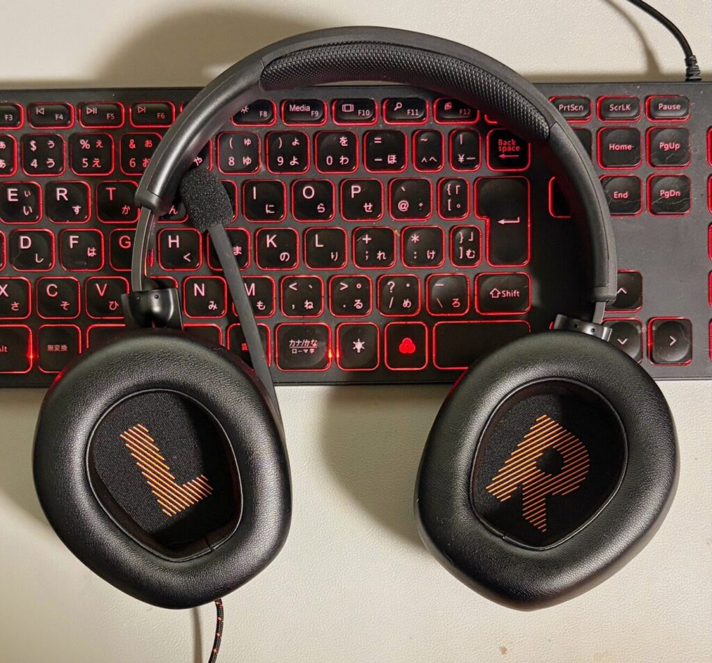 JBL QUANTUM 300（ゲーミングヘッドセット）のアップの写真。背景は赤いバックライトのキーボード。