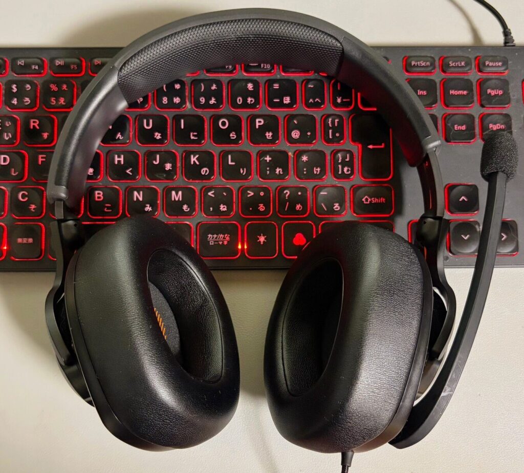 JBL QUANTUM 300(ゲーミングヘッドセット)のアップの写真。背景は赤いバックライトのキーボード。