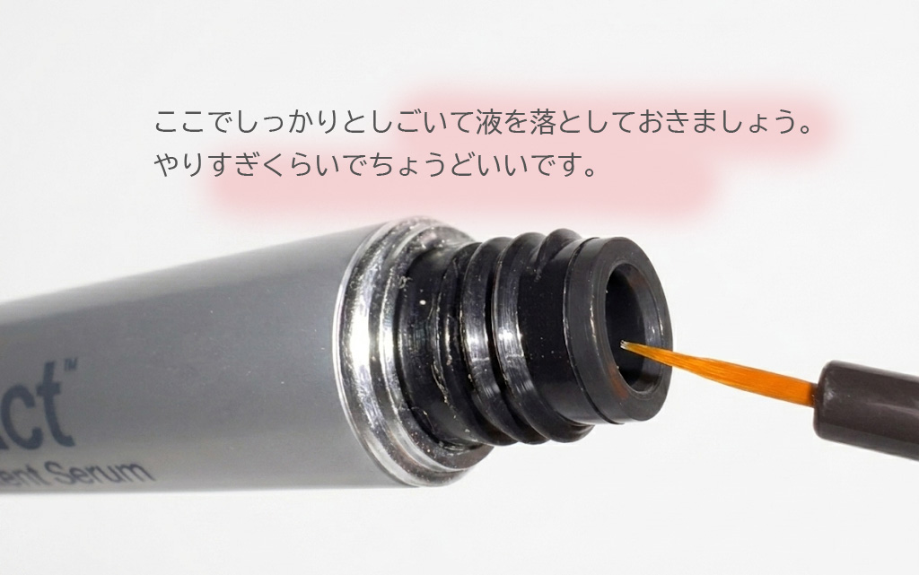 ラッシュアディクトの容器の口で、筆の先をしごいている様子のアップ。