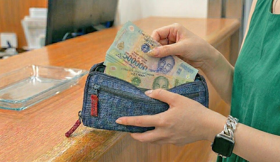 両替したベトナムドンを財布にしまおうとしている女性の手元のアップ。