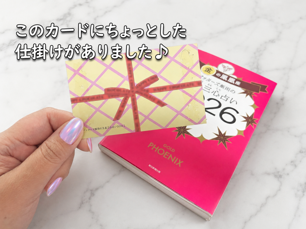 ゲッターズ飯田の五星三心占いの本と付属カードを手に持った様子