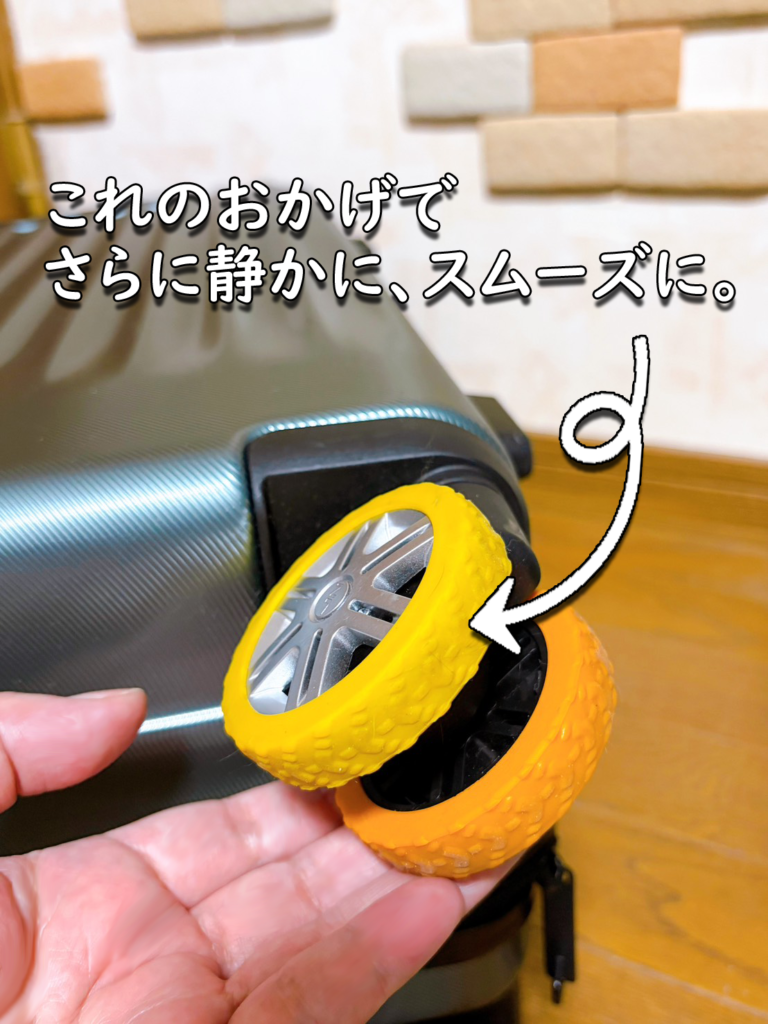 黄色とオレンジのキャスターカバーを付けたスーツケースの車輪のアップ
